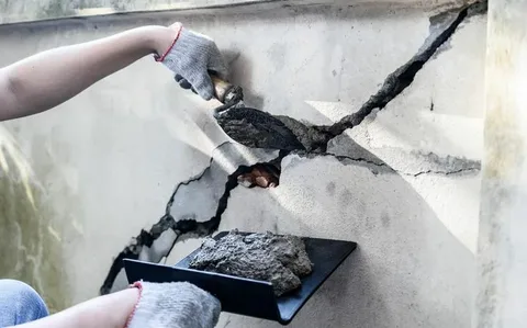 Technician filling a deep wall fracture with patching compound during a routine Concrete Repair