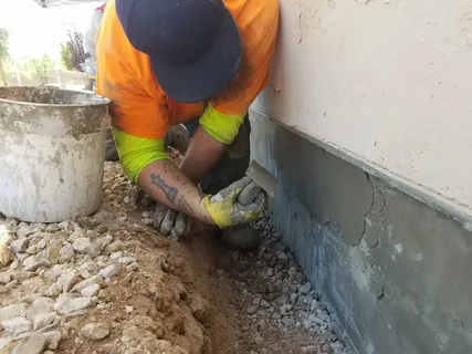 Technician filling a deep wall fracture with patching compound during a routine Concrete Repair